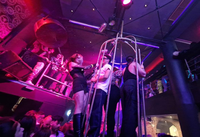 S-Cape gay club: Performers in cage, stage, and crowd under pink lights. Gay nightlife travel advice.