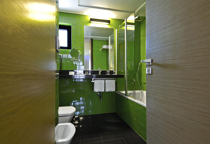 SANA Capitol Hotel Lisbon bathroom. Cheap gay hotel room for 3 adults in Lisbon city center. Green tiles, black floor, bath, toilet and bidet.