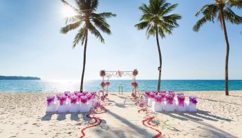 SAii Laguna Phuket beach wedding setup. Chairs, arch, & rose petals on sand. Ideal for gay destination weddings, honeymoons, & LGBTQ+ travel.