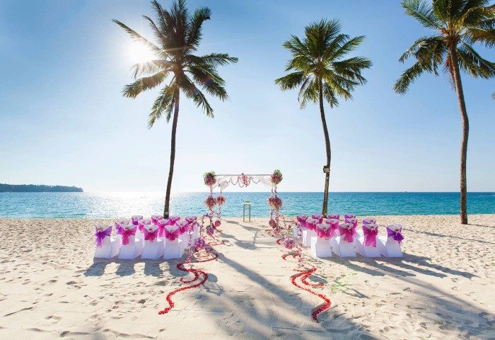 SAii Laguna Phuket beach wedding setup. Chairs, arch, & rose petals on sand. Ideal for gay destination weddings, honeymoons, & LGBTQ+ travel.