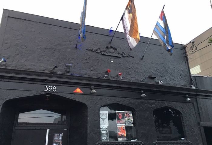 SF Eagle Bar in San Francisco. Dark building exterior with flags. A popular gay bar and leather bar in SOMA for gay men's travel.