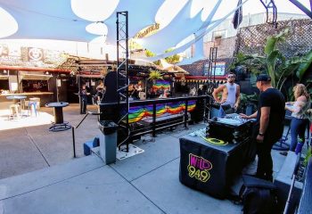 Outdoor patio at SF Eagle Bar in San Francisco. DJ booth with rainbow flag. Gay bar scene, popular spot for gay men's travel.