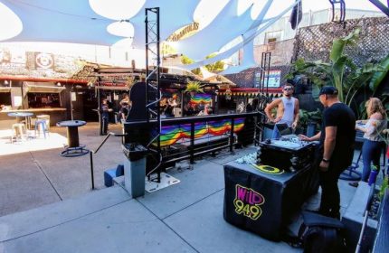 Outdoor patio at SF Eagle Bar in San Francisco. DJ booth with rainbow flag. Gay bar scene, popular spot for gay men's travel.