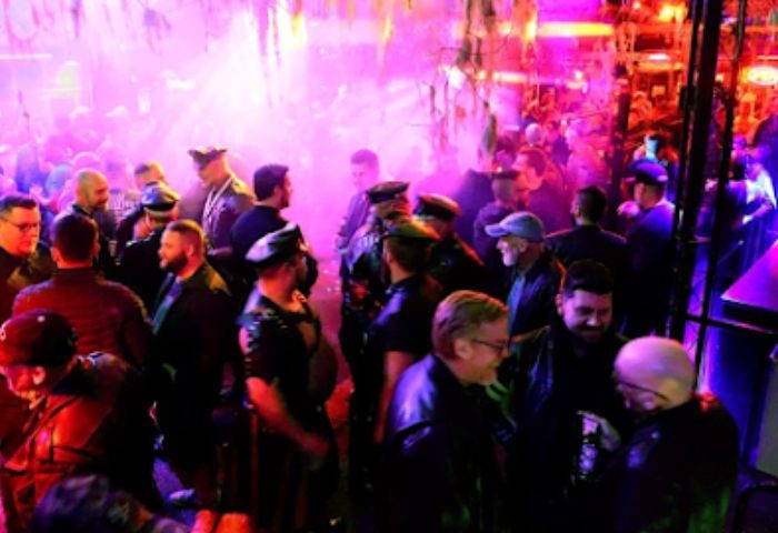 Inside SF Eagle Bar in San Francisco, a popular gay bar. Leather and Levi's night, men in leather gear, hats, and caps, enjoying the ambiance.