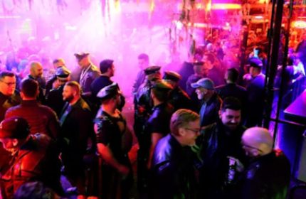 Inside SF Eagle Bar in San Francisco, a popular gay bar. Leather and Levi's night, men in leather gear, hats, and caps, enjoying the ambiance.