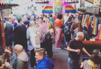 Crowded gay bar in San Francisco. Rainbow flags adorn the outdoor patio at Mix bar. Gay travel destination for men's nightlife.