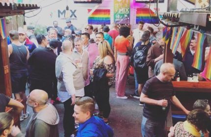 Crowded gay bar in San Francisco. Rainbow flags adorn the outdoor patio at Mix bar. Gay travel destination for men's nightlife.