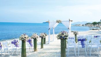 SAii Koh Samui Villas wedding setup. Beach wedding at SKS, white chairs with violet bows, floral arrangements, and a white canopy.