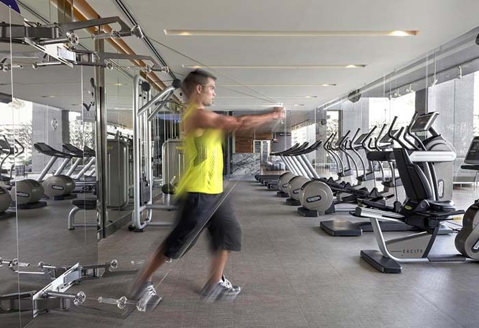 SO/ Bangkok hotel gym. Man works out with cable machine. Fitness center at one of the best gay-friendly hotels in Bangkok.