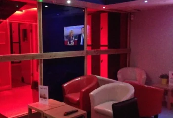 Inside Sailors Sauna, a gay sauna, with red lighting, TVs, and seating. A relaxing space for gay men to unwind and socialize.