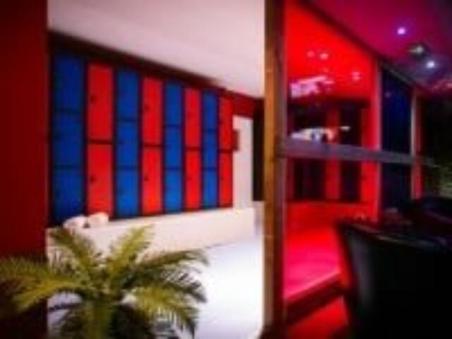 Interior of Sailors Sauna, a gay sauna. Red and blue lockers line the wall. Red lighting illuminates the sauna area. Gay travel advice.