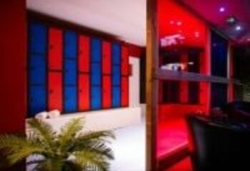 Interior of Sailors Sauna, a gay sauna. Red and blue lockers line the wall. Red lighting illuminates the sauna area. Gay travel advice.