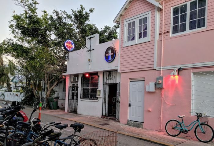 Saloon 1, a Key West gay bar in Florida. The bar's entrance is visible, with bikes parked nearby. Pink building next door.