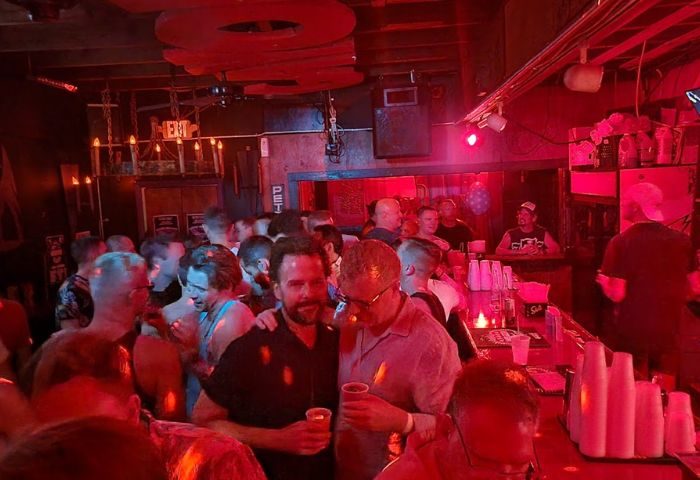 Saloon 1 Gay Bar in Key West, Florida. Interior shot of a crowded gay bar with red lighting, men drinking, and socializing.