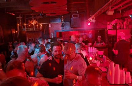 Saloon 1 Gay Bar in Key West, Florida. Interior shot of a crowded gay bar with red lighting, men drinking, and socializing.