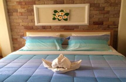 Samet Inn room: Blue-themed bed with towel art, brick wall, and floral art. Gay travel lodging at Samet Inn. Samet-Inn.jpg.