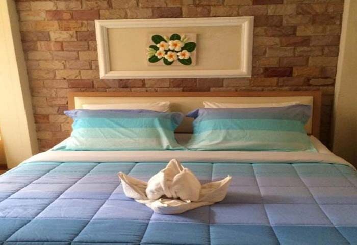 Samet Inn room: Blue-themed bed with towel art, brick wall, and floral art. Gay travel lodging at Samet Inn. Samet-Inn.jpg.