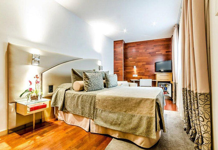 Sansi Diputacio Hotel room in Barcelona's Eixample. Best gay honeymoon hotel with a bed, wood paneling, and modern decor. Gay travel advice.