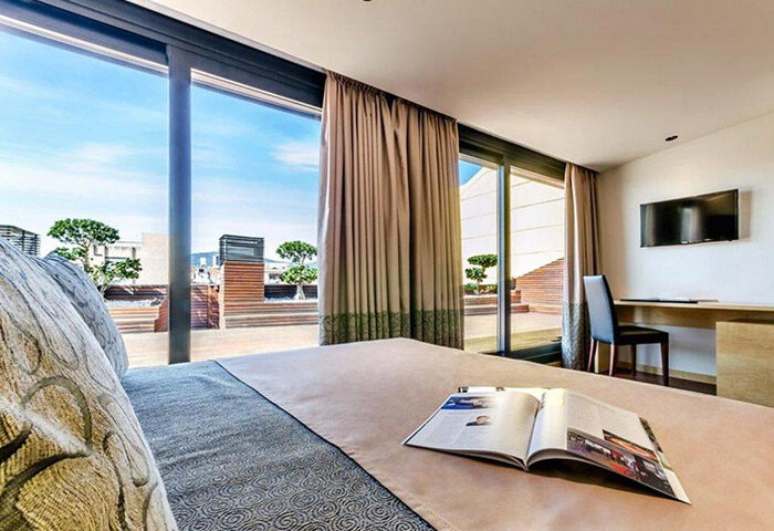 Sansi Diputacio Hotel room, Barcelona. Most booked gay hotel near gay bars. Open magazine on bed, terrace view. Gay travel.