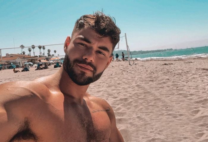 Sasha Bloom by Sasha: Gay travel influencer shirtless on beach. Outdoor photo of handsome, bearded man. Gay travel advice, beach vacation.