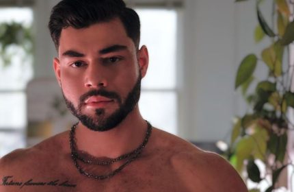 Sasha Bloom by Sasha: Portrait of a handsome, muscular gay man with a beard and chest tattoo. Perfect for gay travel inspiration.