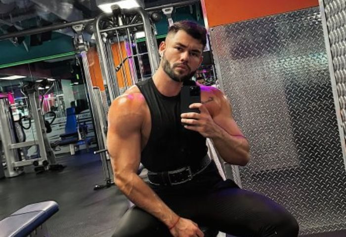 Sasha Bloom by Sasha: Muscular gay man takes a selfie at the gym. He's wearing a black tank top and pants. Gay travel advice.