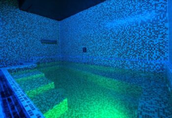 Sauna Apolo Lisbon: Mosaic-tiled pool with steps, illuminated with blue and green lights, creating a vibrant and inviting atmosphere for gay travelers.