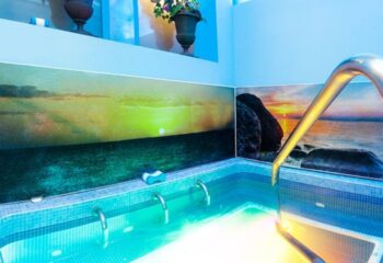 Sauna Bruc, Barcelona: Interior of a gay sauna with a small pool, metal ladder, and scenic sunset mural. Relaxing spa day for gay travelers.