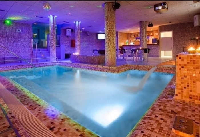 Sauna Casanova Barcelona: Interior view of the gay sauna with a pool, bar, and ambient lighting. A relaxing gay travel destination.