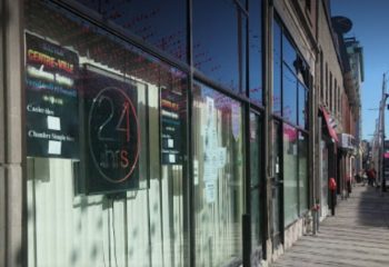 Montreal gay sauna in Centre-Ville. The glass front of the building has a sign that says 24 hrs. Cruising spot for gay men in Montreal.