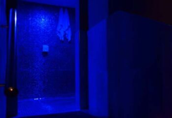 Blue-lit sauna interior at Condal, a gay sauna in Barcelona. Towels hang on the textured wall, enhancing the ambiance.