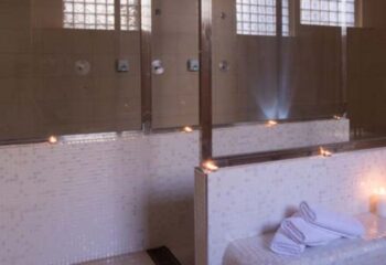 Condal Gay Sauna in Barcelona: Showers with glass block windows & candles. Towels on a bench. Gay travel advice for men.