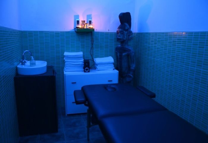 Madrid gay sauna in Lavapies. Interior view with massage table, sink, towels, and decorative statue under blue lighting. Relaxing spa.