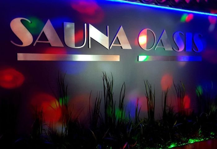 Sauna Oasis in Montreal: Signage with colorful lighting and plants. Gay sauna travel advice for men seeking relaxation and social experiences.