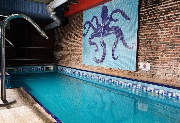 Gay sauna in Madrid: Octopus mosaic above a pool. Brick walls, blue tile. A popular gay travel destination for men's wellness.