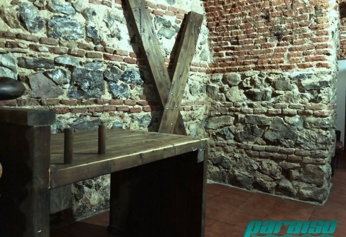 Gay Sauna Paraiso in Madrid: Stone walls, wooden table, and cross in this gay sauna. A unique space for gay men's travel adventures.