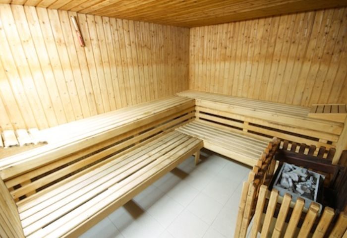 Sauna interior with wooden benches. Gay sauna in Gran Canaria, Portugal. Relaxation and wellness for gay men travelers. Hot stones in the corner.