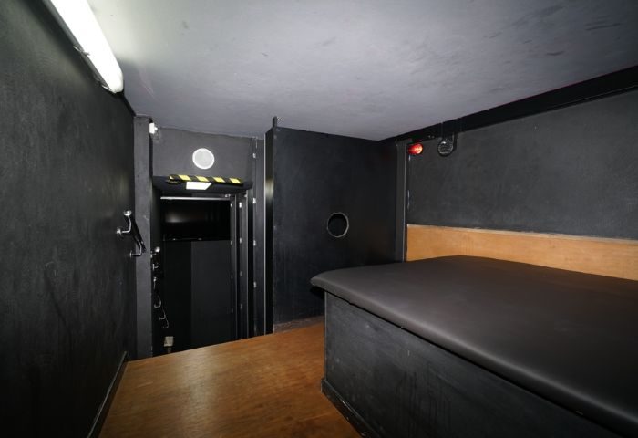 Gay sauna in Gran Canaria. Dark room interior with bench, doorway, and low light. Gay travel destination for men.