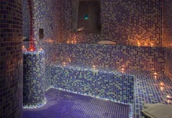 Barcelona Gay Sauna Thermas: Mosaic-tiled sauna interior with benches, candles, & ambient lighting. A relaxing spa experience for gay travelers.