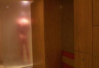 Saunabar London Portsea: Blurred figure behind glass in gay sauna showers. Lockers visible. Gay travel advice for London's gay sauna scene.