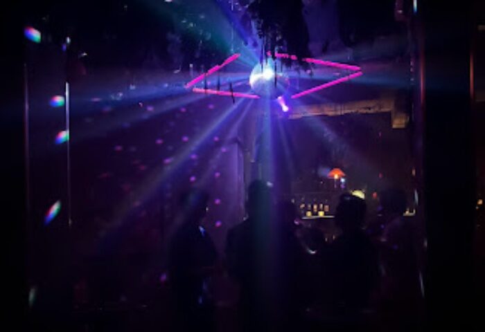 Hanoi gay nightlife: Savage club interior. Silhouetted figures under a disco ball with pink lights. Gay travel advice for Hanoi, Vietnam.
