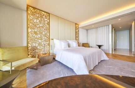 Savoy Palace Hotel Madeira, gay-friendly. Luxurious bedroom with a king-size bed, golden accents, and modern design. Perfect for gay travel.