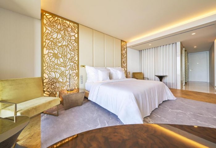 Savoy Palace Hotel Madeira, gay-friendly. Luxurious bedroom with a king-size bed, golden accents, and modern design. Perfect for gay travel.
