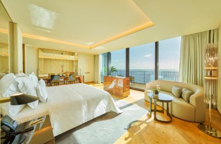 Savoy Palace Hotel Madeira bedroom. Luxury gay travel destination. Ocean view suite with balcony, sofa, and king bed. Upscale resort.