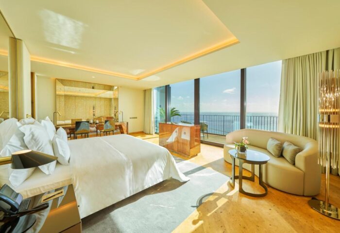 Savoy Palace Hotel Madeira bedroom. Luxury gay travel destination. Ocean view suite with balcony, sofa, and king bed. Upscale resort.