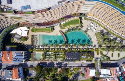 Aerial view of Savoy Palace Madeira, a gay-friendly hotel. Pools, palm trees, and modern architecture offer a luxurious travel experience.