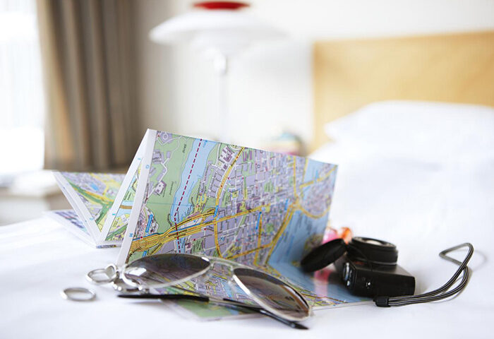 Scandic Copenhagen hotel room. Map, sunglasses, camera on bed. Gay-friendly hotel near Vesterbro. Travel planning in Copenhagen.