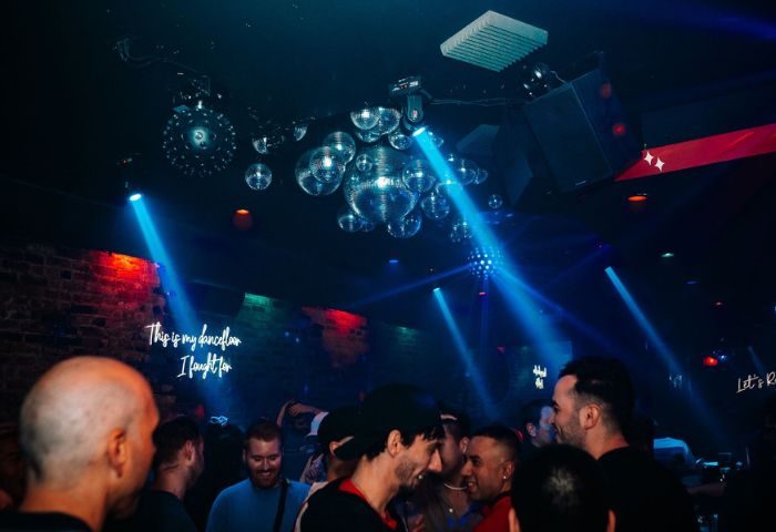 Scarlet Bar gay party in Chicago. Men gather under disco balls and neon lights at a vibrant gay bar. Nightlife and travel for gay men.