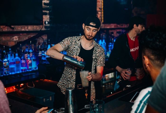 Bartender pouring drink at Scarlet Bar, a gay party in Chicago. Nightlife scene with men enjoying drinks. Gay travel advice.