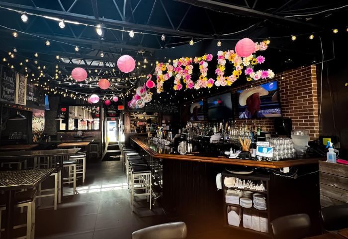 Interior of Score on Davie, a Vancouver sports bar. PRIDE in flowers, pink lanterns, bar stools, TVs, and string lights.